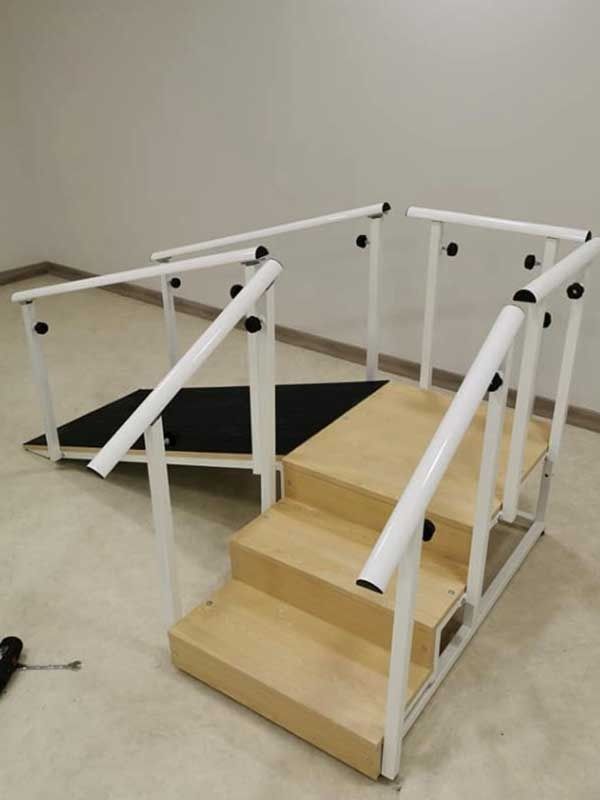 Escalera de rehabilitación de madera y color blanco con pasamanos y rampa, para la práctica de fisioterapia.