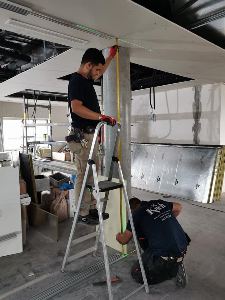 Dos trabajadores de la construcción miden y trabajan en una columna y un techo en un edificio sin terminar.