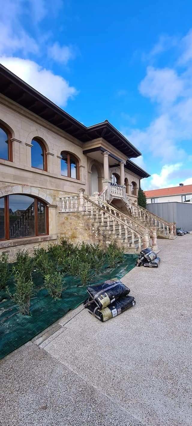 Edificio de piedra con escaleras y un pequeño porche en un día luminoso y soleado.