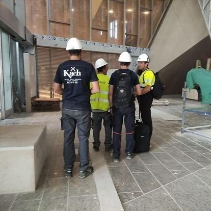Cuatro trabajadores de la construcción con cascos dentro de un edificio en construcción.