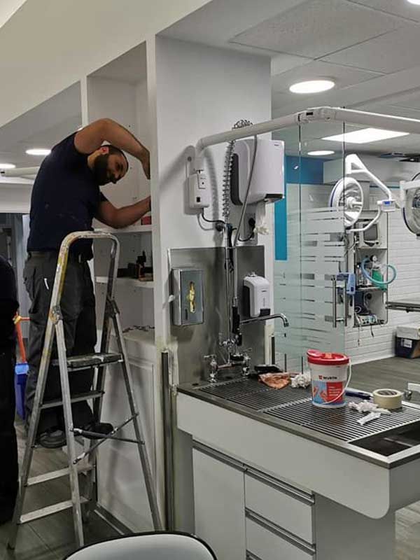 Hombre en escalera trabajando en estantes en una clínica veterinaria,