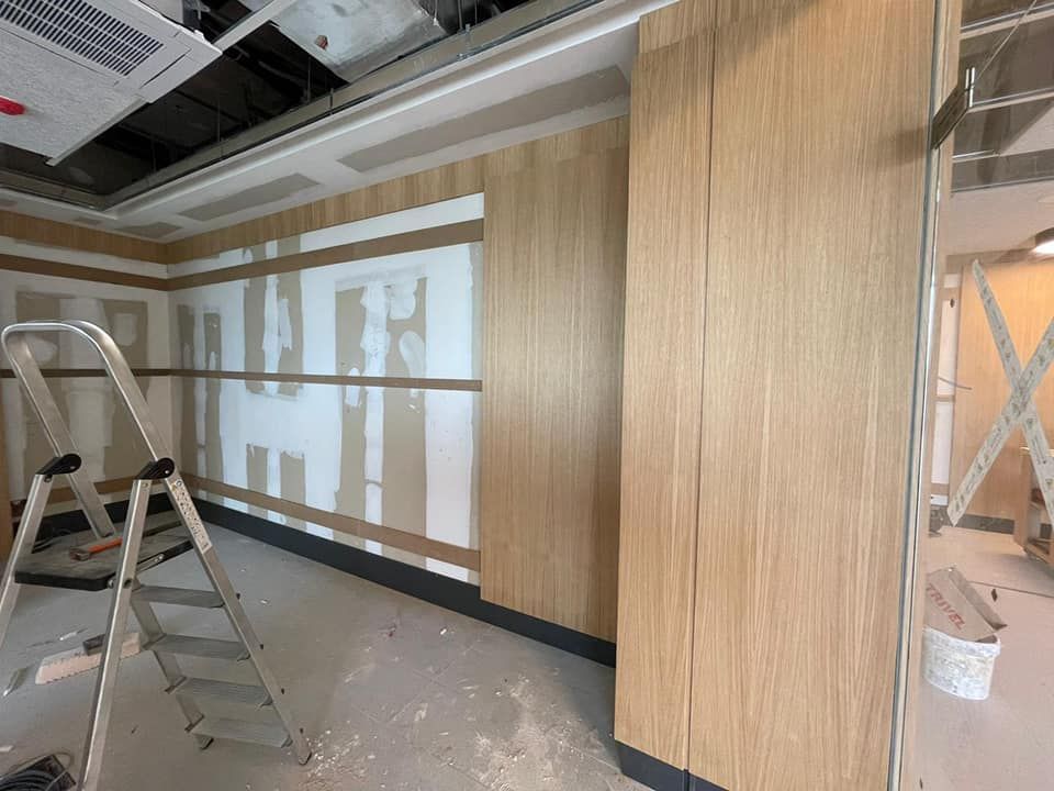 Habitación interior en construcción con paneles de madera en las paredes, escalera y techo a la vista.