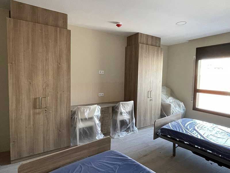 Un dormitorio con dos camas, dos sillas y dos grandes armarios de madera.