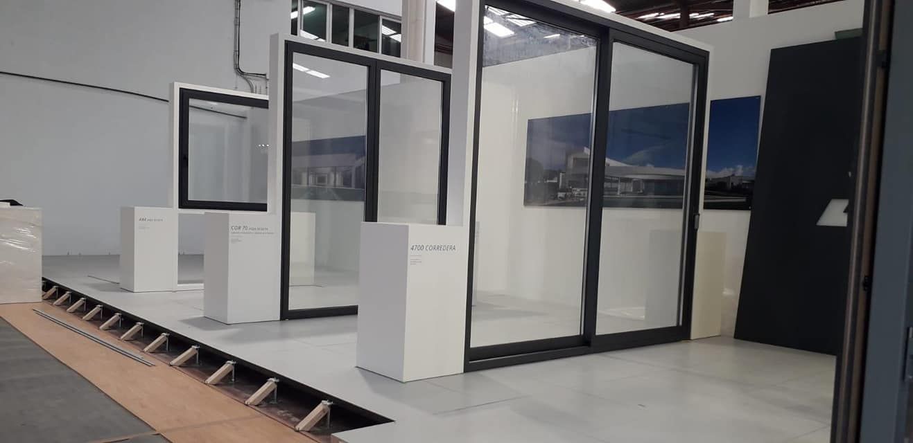 Vista interior de una galería de arte con escaparates de cristal y pedestales blancos.