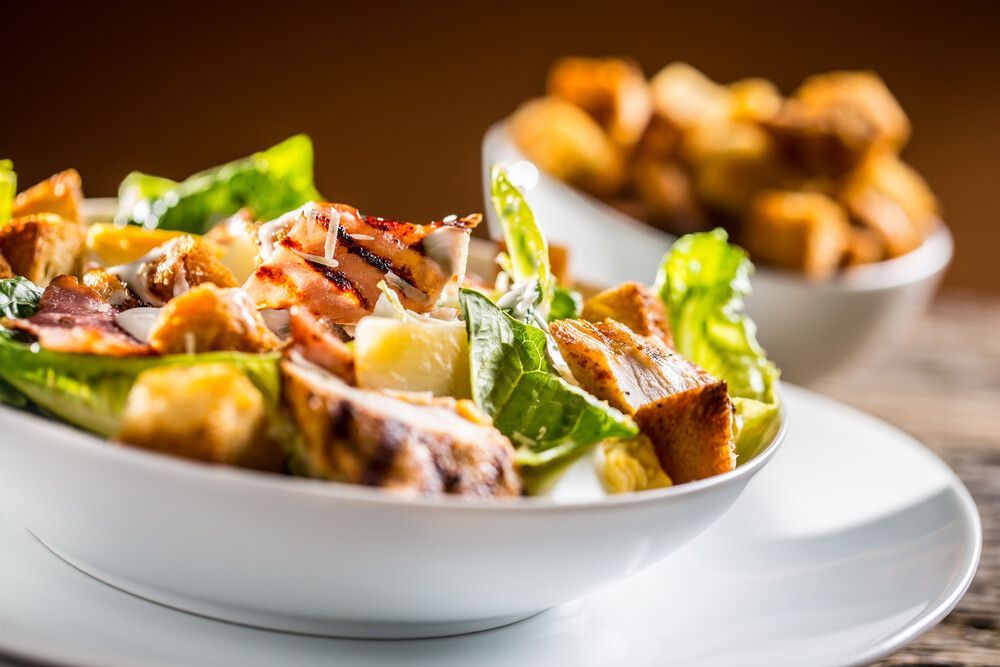 Un primer plano de una ensalada en un tazón en un plato sobre una mesa.