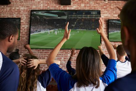 Un grupo de personas está viendo un partido de fútbol en un televisor.