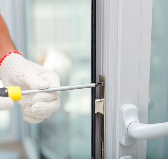 Una persona está usando un destornillador para arreglar una puerta.