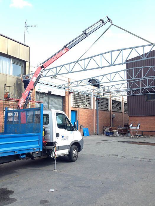 Un camión con una grúa acoplada en la parte trasera está estacionado frente a un edificio.