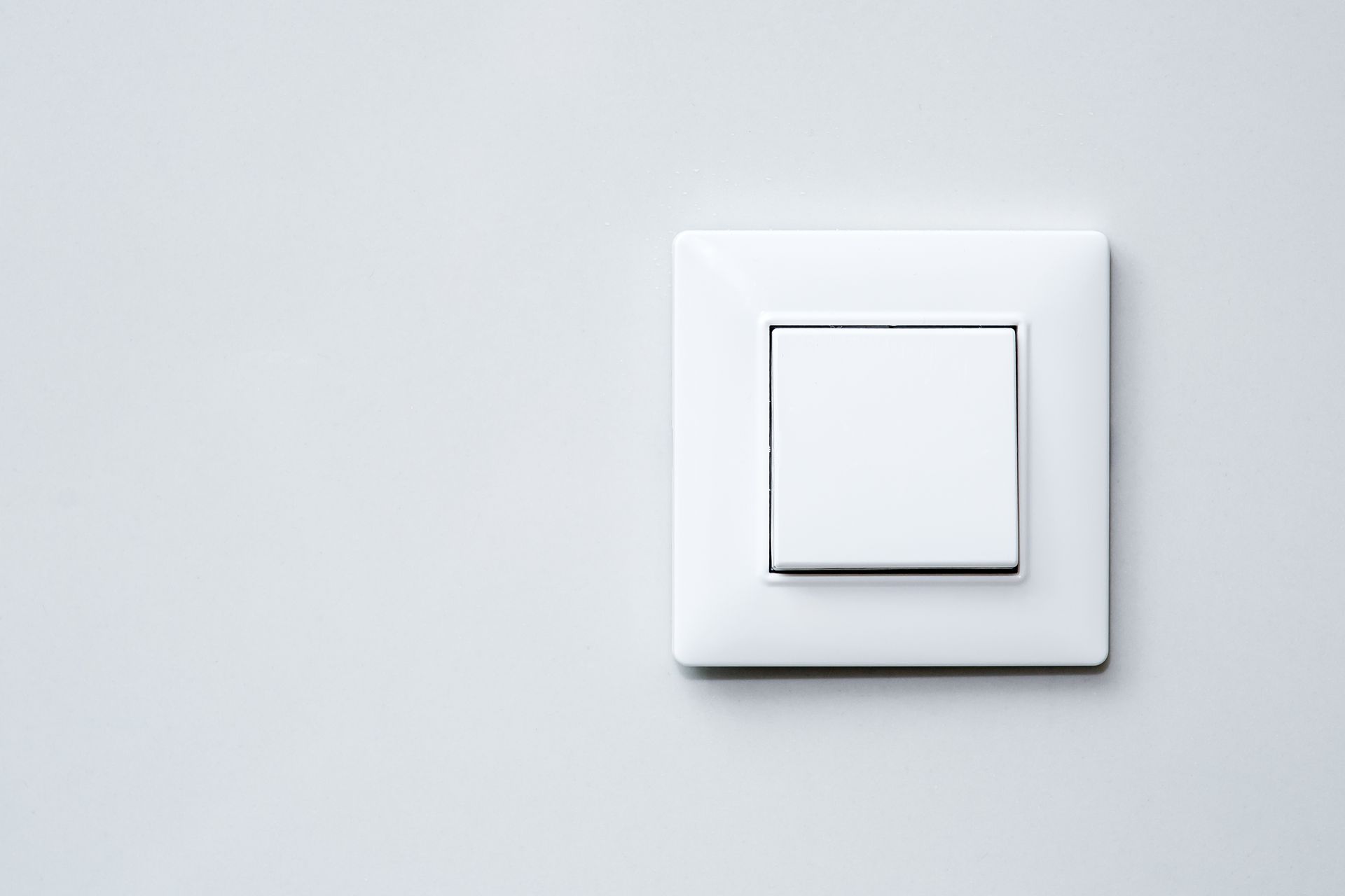 Interrupteur blanc sur un mur gris clair