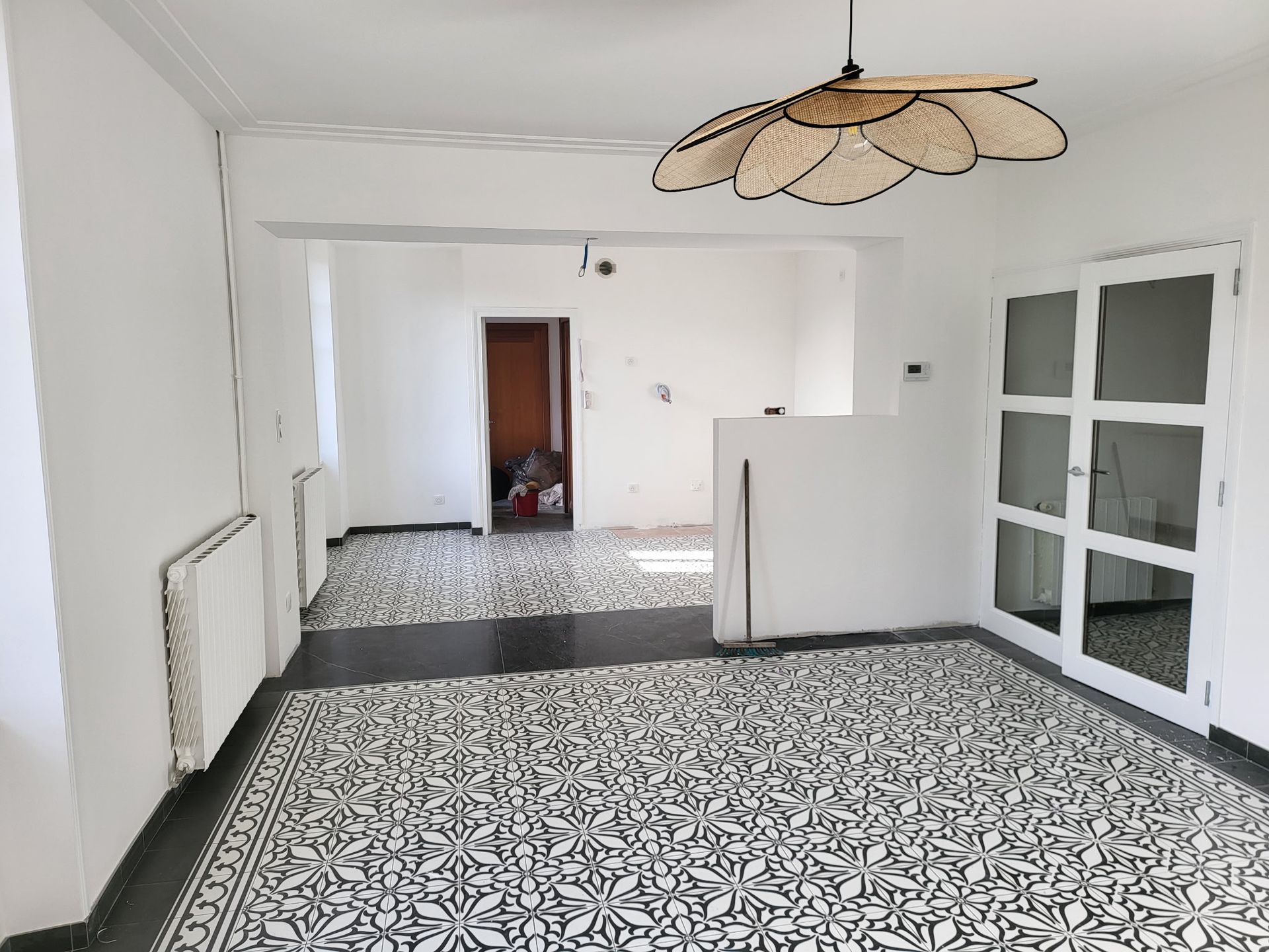 Pièce intérieure avec carrelage au sol à motifs, murs et luminaire décoratif.