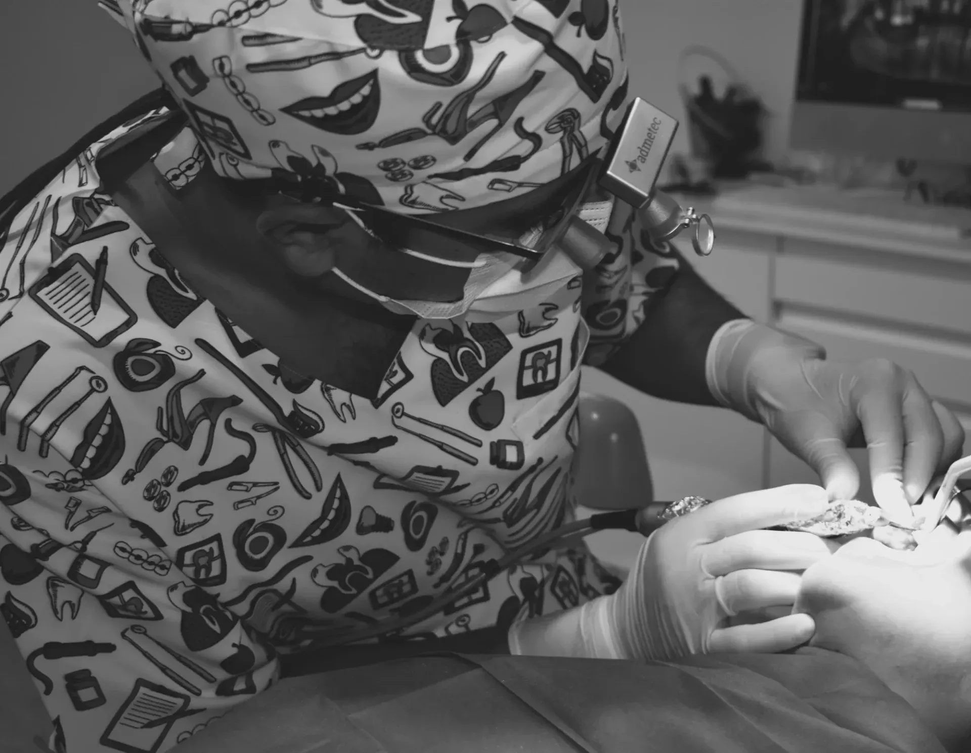Una fotografía en blanco y negro de un dentista trabajando en los dientes de un paciente.