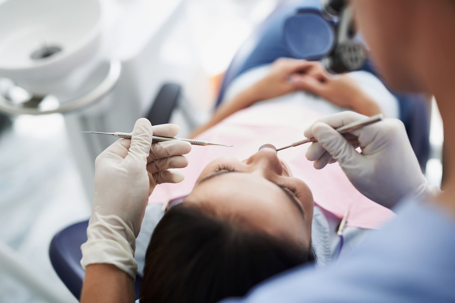 Una mujer está acostada en una silla dental mientras un dentista le examina los dientes.