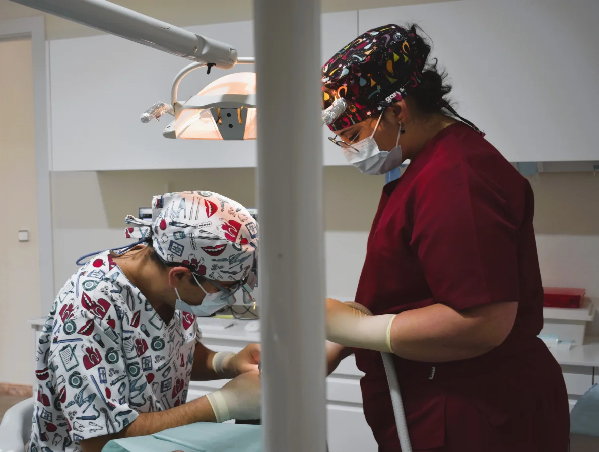 Dos dentistas están trabajando con un paciente en un consultorio dental.