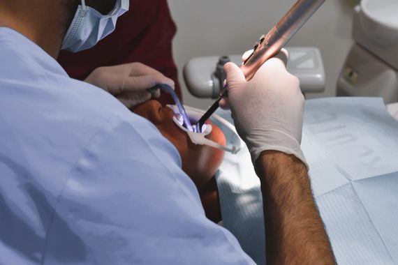 Un dentista está trabajando en los dientes de un paciente en un consultorio dental.