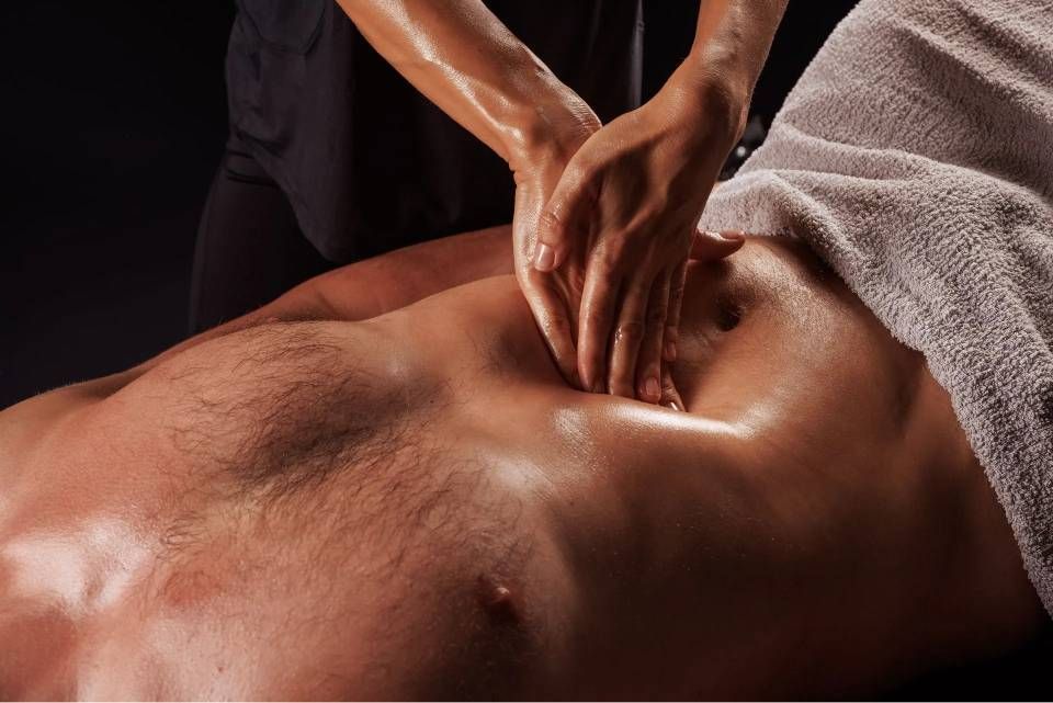 Des mains massent le dos d'une personne allongée sur le ventre sous une serviette
