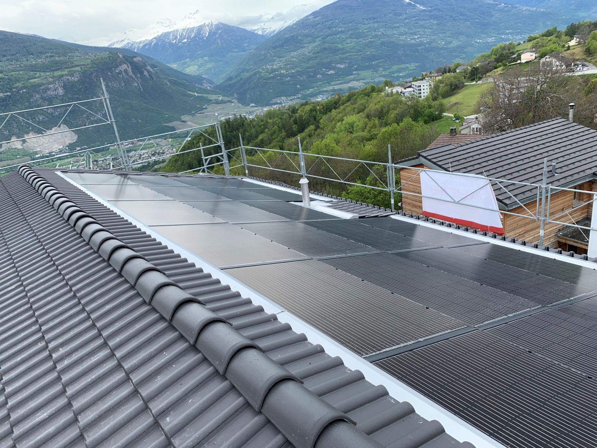 Panneaux solaires sur un toit de tuiles avec une montagne en arrière-plan.