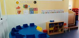 Un aula con una mesa redonda y sillas y un estante.