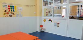 Un aula con mesas y sillas naranjas y una ventana.