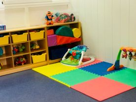Una habitación infantil con una alfombra de juegos colorida y un andador.