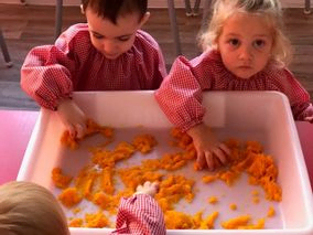 Un niño y una niña están jugando con zanahorias en una bandeja.