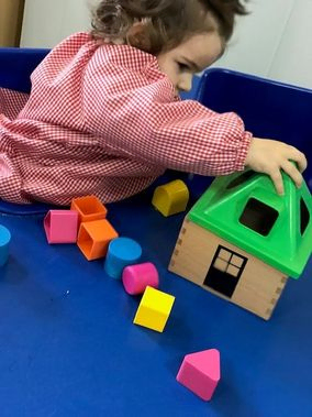 Una niña está jugando con bloques en una mesa azul.