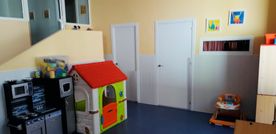 Una habitación con una casa de juguetes y un andador de bebé dentro.