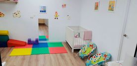 Una habitación de bebé con cuna, hamaca y juguetes.