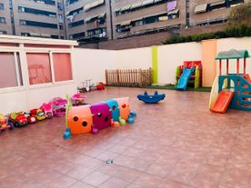Un parque infantil con tobogán, caballo balancín y otros juguetes.
