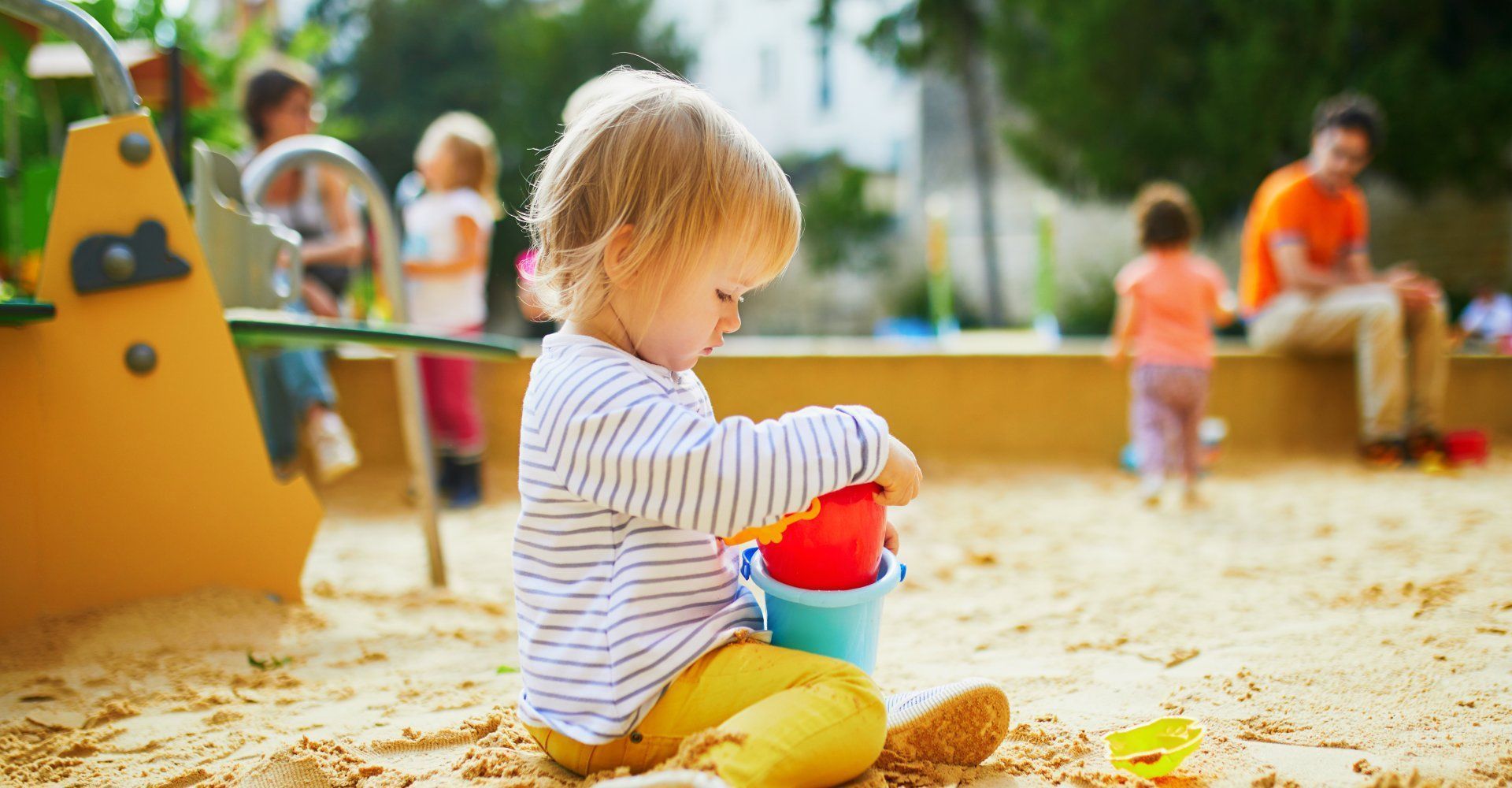 Kind spielt mit Spielzeug im Sandkasten auf dem Spielplatz.