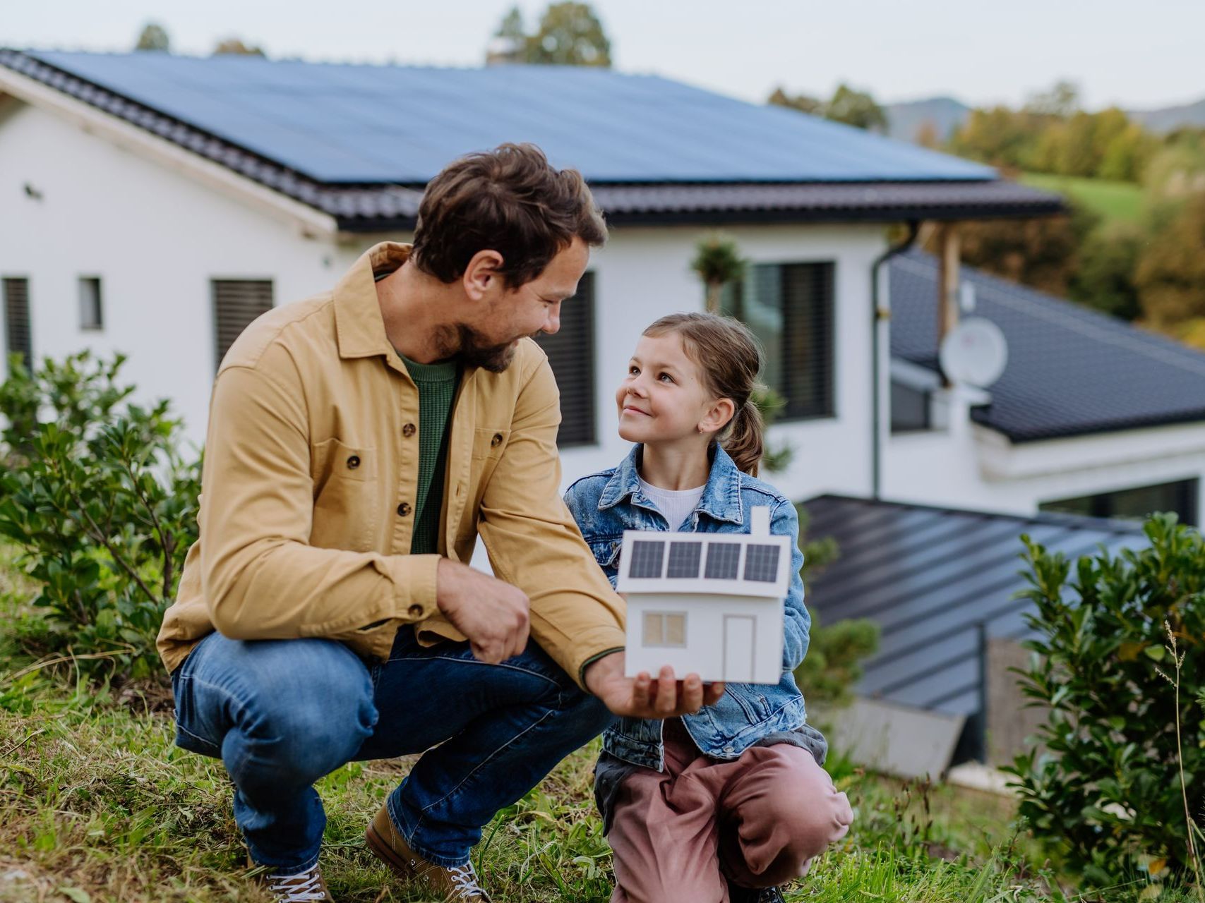 Famille devant une maison avec panneaux solaires sur toiture