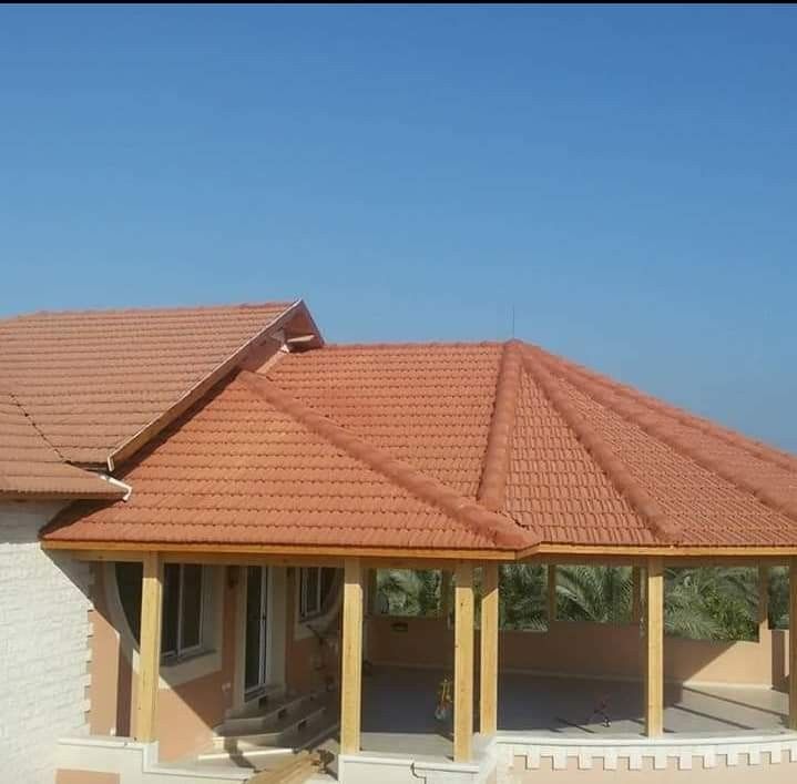 Casa con tejado de tejas de terracota y porche cubierto bajo un cielo azul despejado.