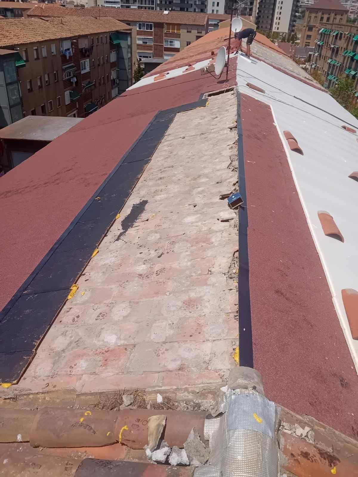 Pasarela en la azotea con paneles metálicos rojos y blancos y una franja central desgastada entre edificios de apartamentos.