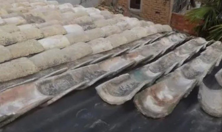 Hileras de largas estructuras de hormigón o piedra desgastadas por el tiempo, dispuestas sobre una lona al aire libre, con una pared de ladrillos al fondo.