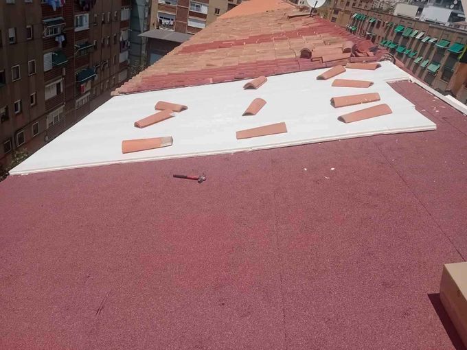 Azotea roja con manchas de nieve dispersas junto a edificios de apartamentos de ladrillo.