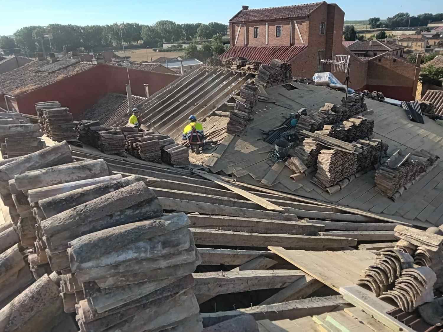 Escombros de un edificio de ladrillos derrumbado, con trabajadores inspeccionando los restos en un día soleado.