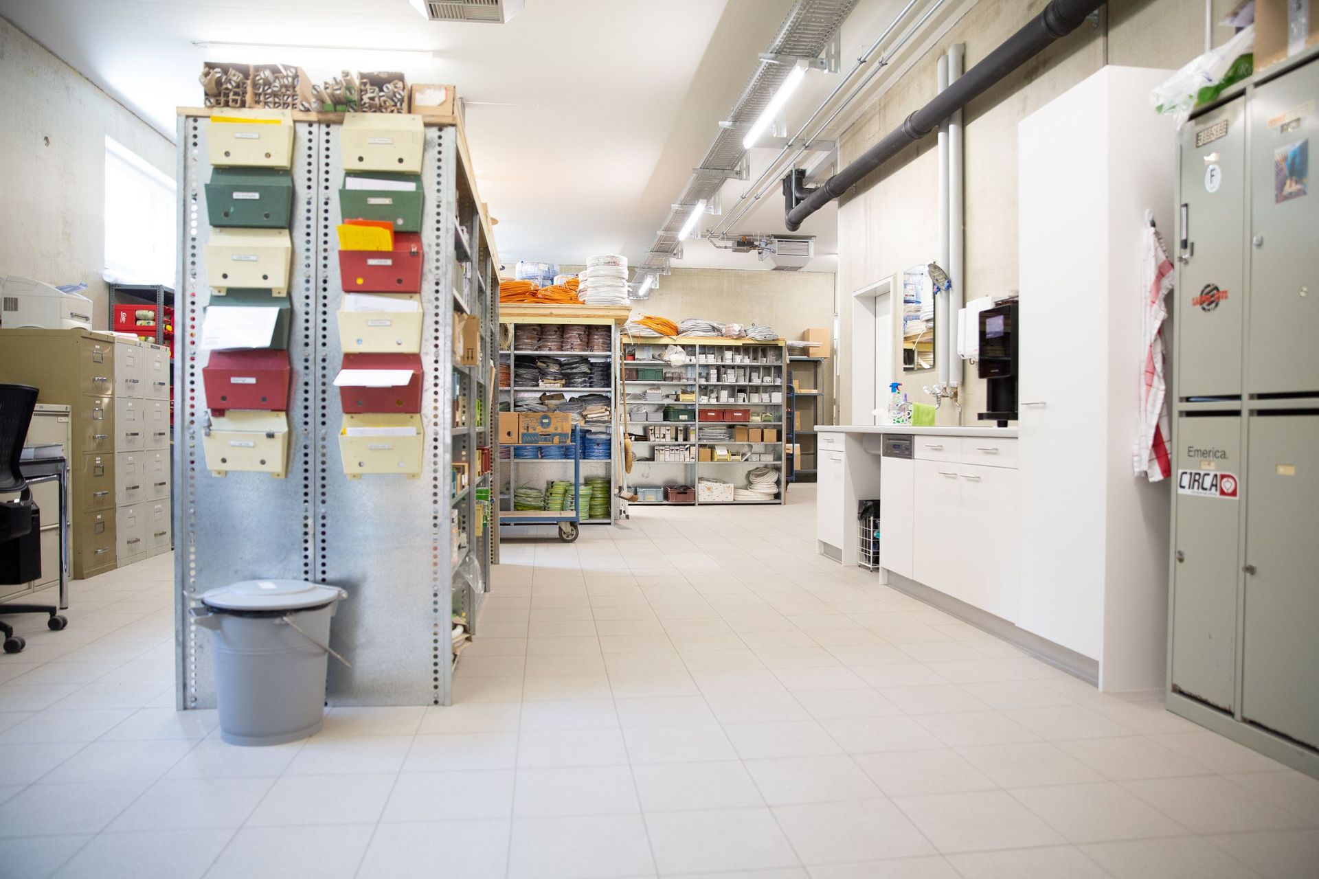 Ein gut beleuchteter Innenraum eines Lagerraums oder Büros. Regale bieten Platz für verschiedene Gegenstände. Briefkästen sin