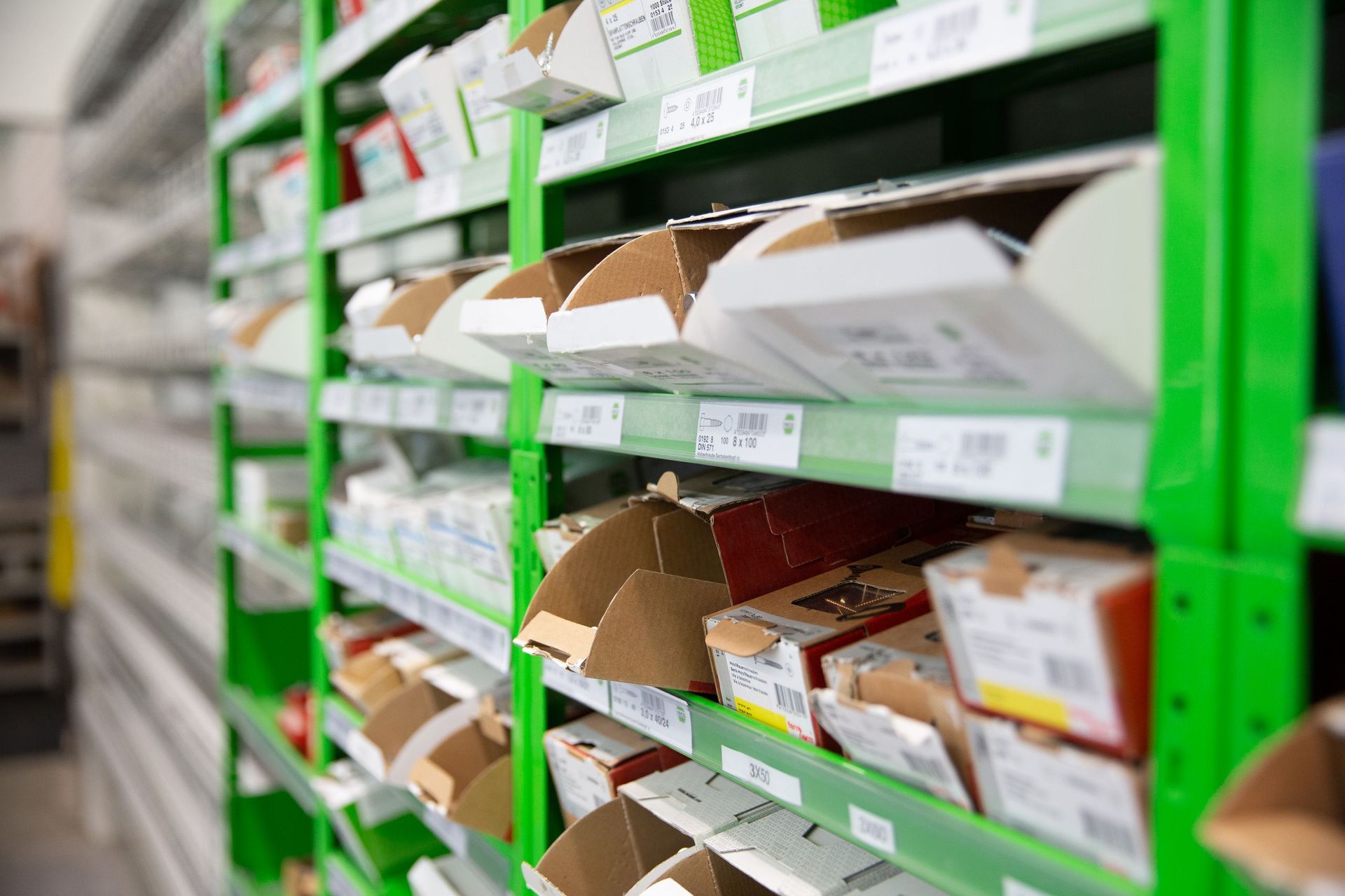 Grüne Regale voller Kartons in einem Lagerhaus, die auf die Lagerung und Organisation von Lagerbeständen hindeuten.