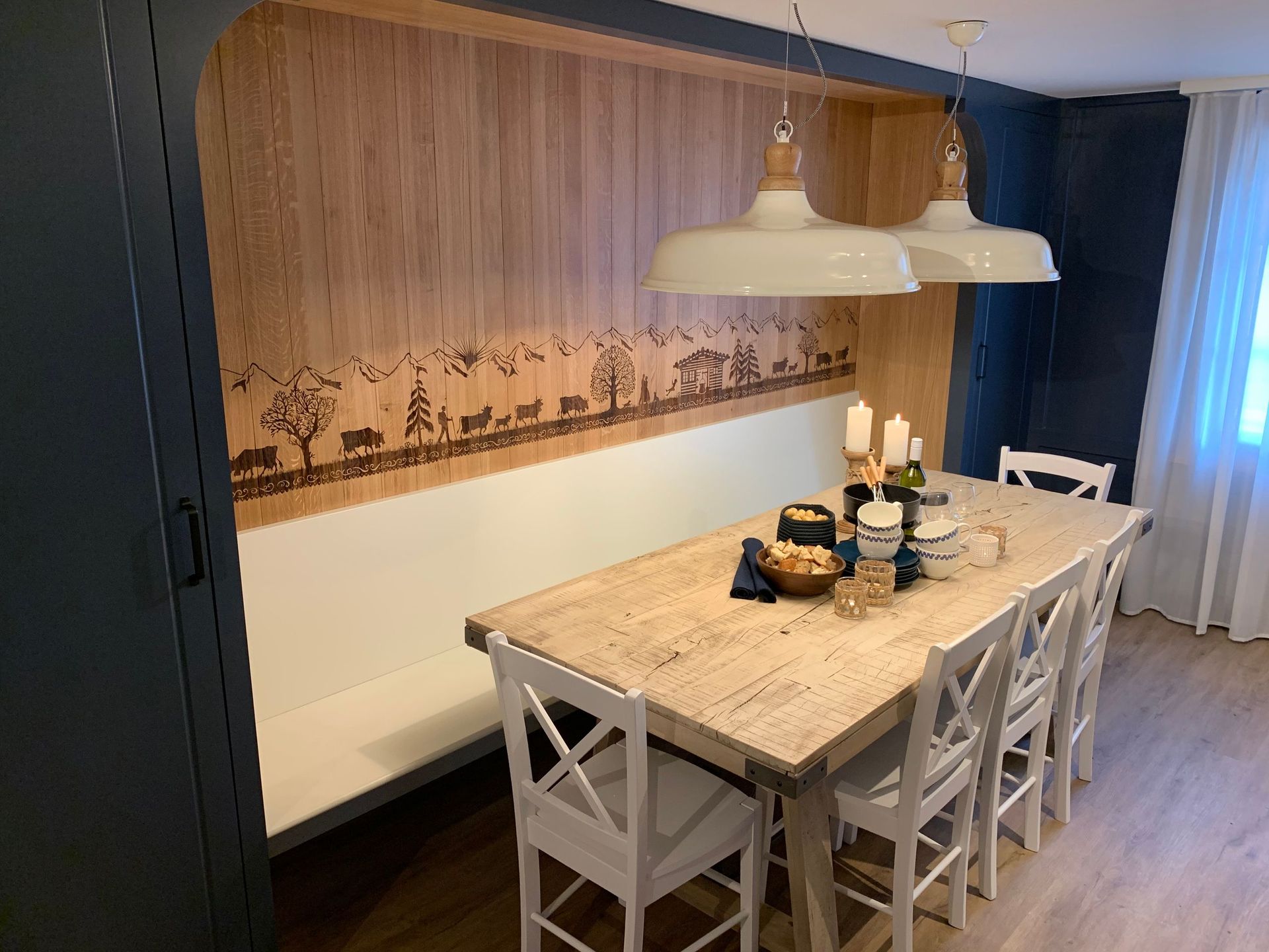 Essbereich mit einem hellen Holztisch mit weißen Stühlen, einer eingebauten Bank und einer holzgetäfelten Wand mit dekorative