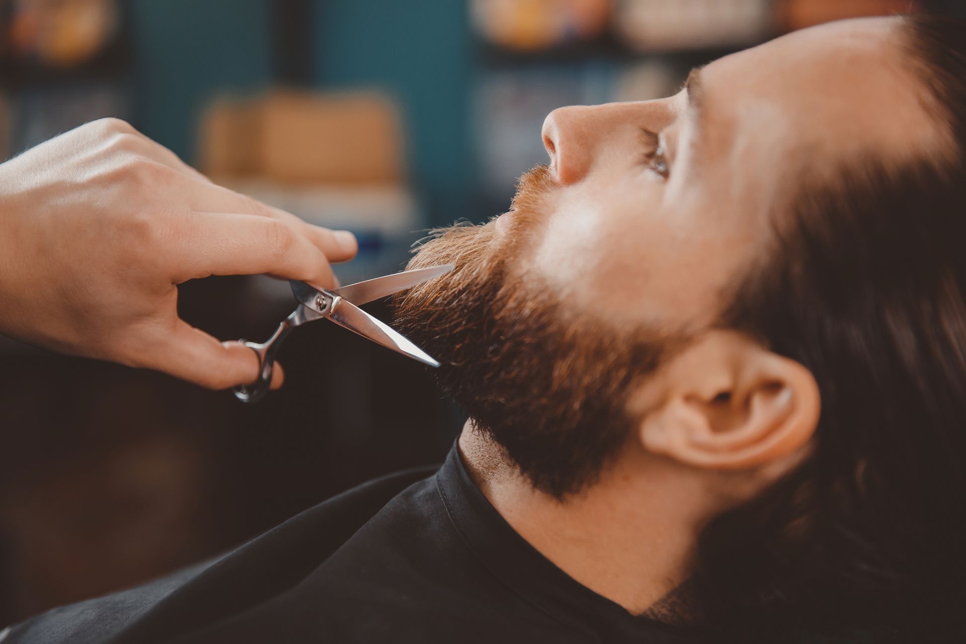 Un hombre se deja cortar la barba por un barbero con unas tijeras.