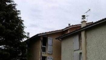 Toits d’immeubles résidentiels avec des cheminées et une antenne sous un ciel nuageux