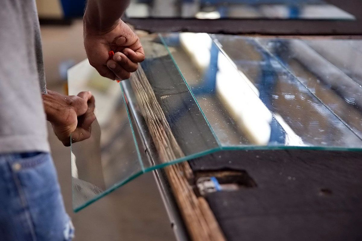 Ouvrier en train de découper une plaque de verre en plusieurs panneaux