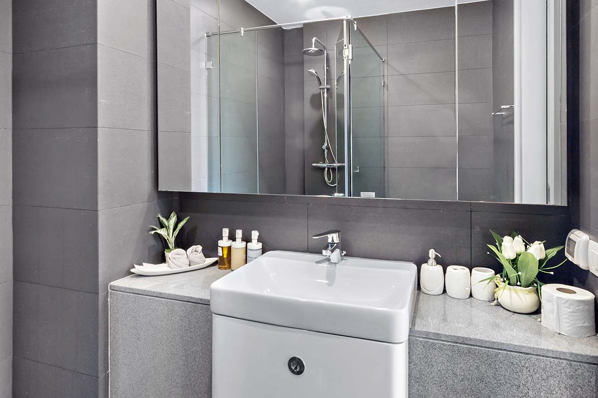 Cabine de douche en verre vue dans le reflet d'un grand miroir au-dessus du lavabo