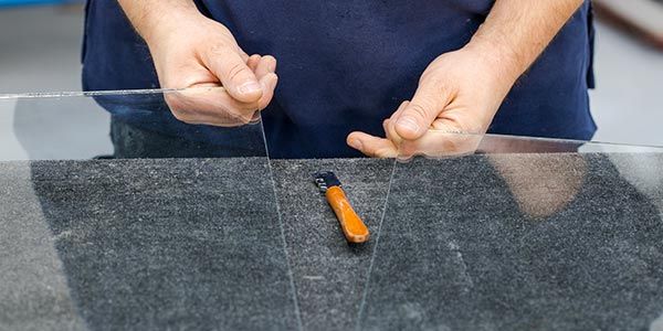 Ouvrier tenant un morceau de plaque de verre dans chaque main entre ses doigts