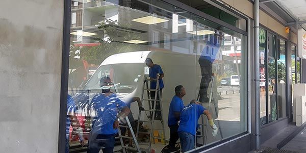 Plusieurs personnes en train d'installer les grandes vitres extérieures d'un magasin