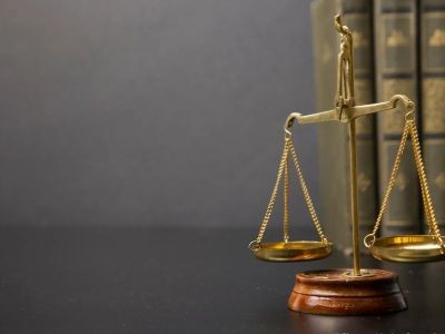 Rechtsanwälte Gerngroß • Dr. Höfler - Goldwaage und Rechtsbücher vor grauem Hintergrund