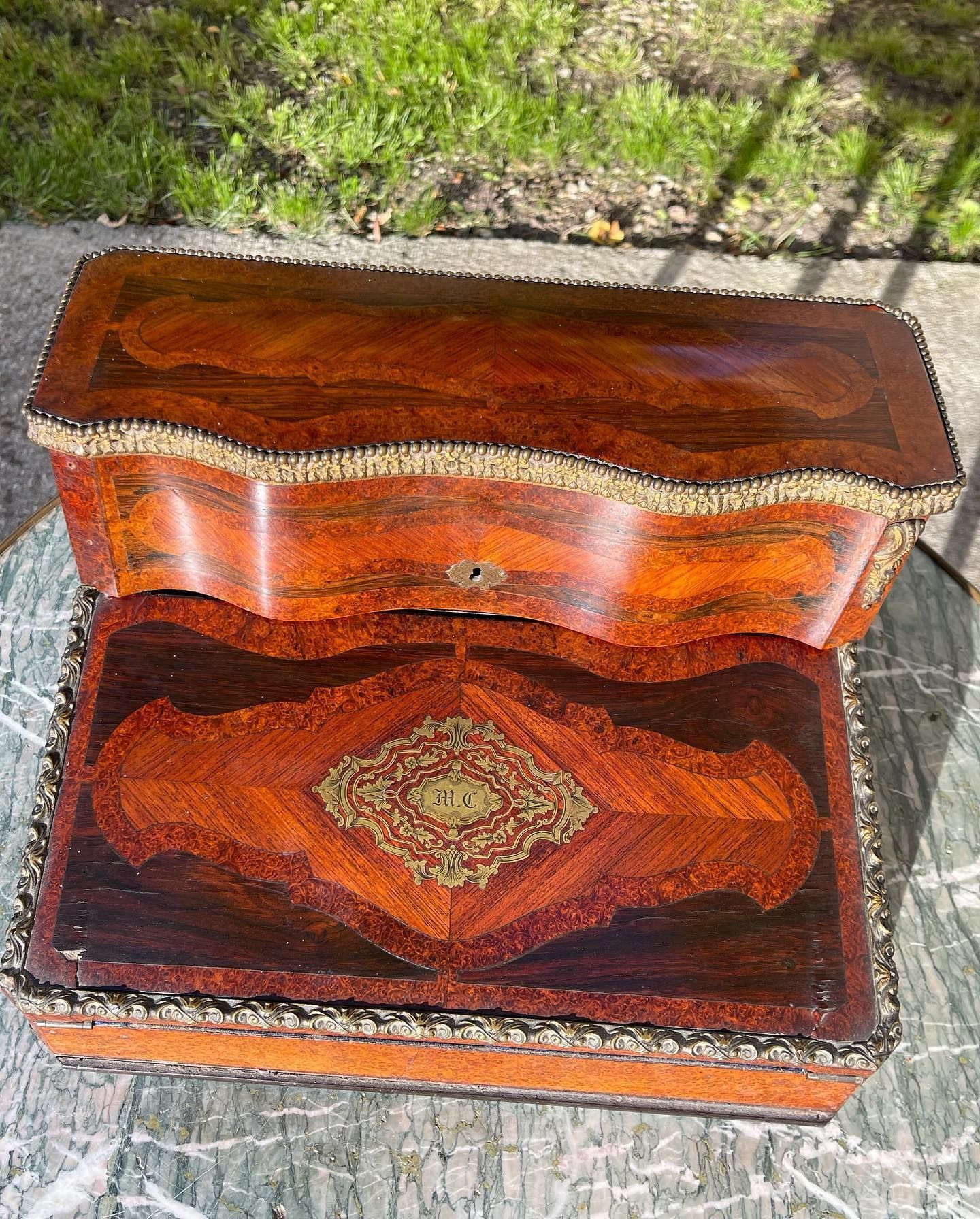 Deux coffrets en bois finement ouvragés, superposés l'un sur l'autre, ornés de garnitures en laiton. Celui du dessus est verrouillé.