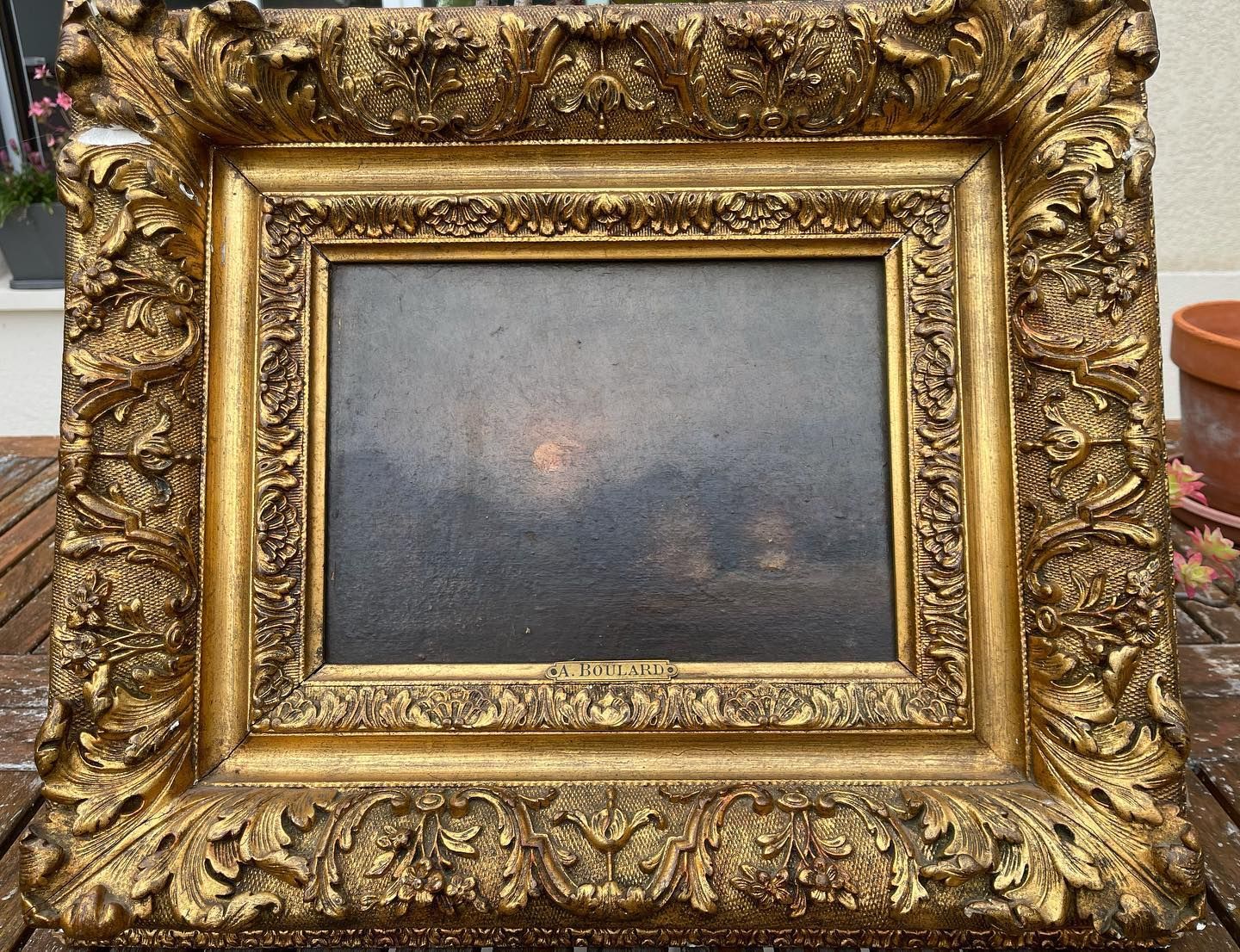 Tableau orné, encadré de couleur or ; ciel sombre, peut-être orageux, avec un centre plus clair.