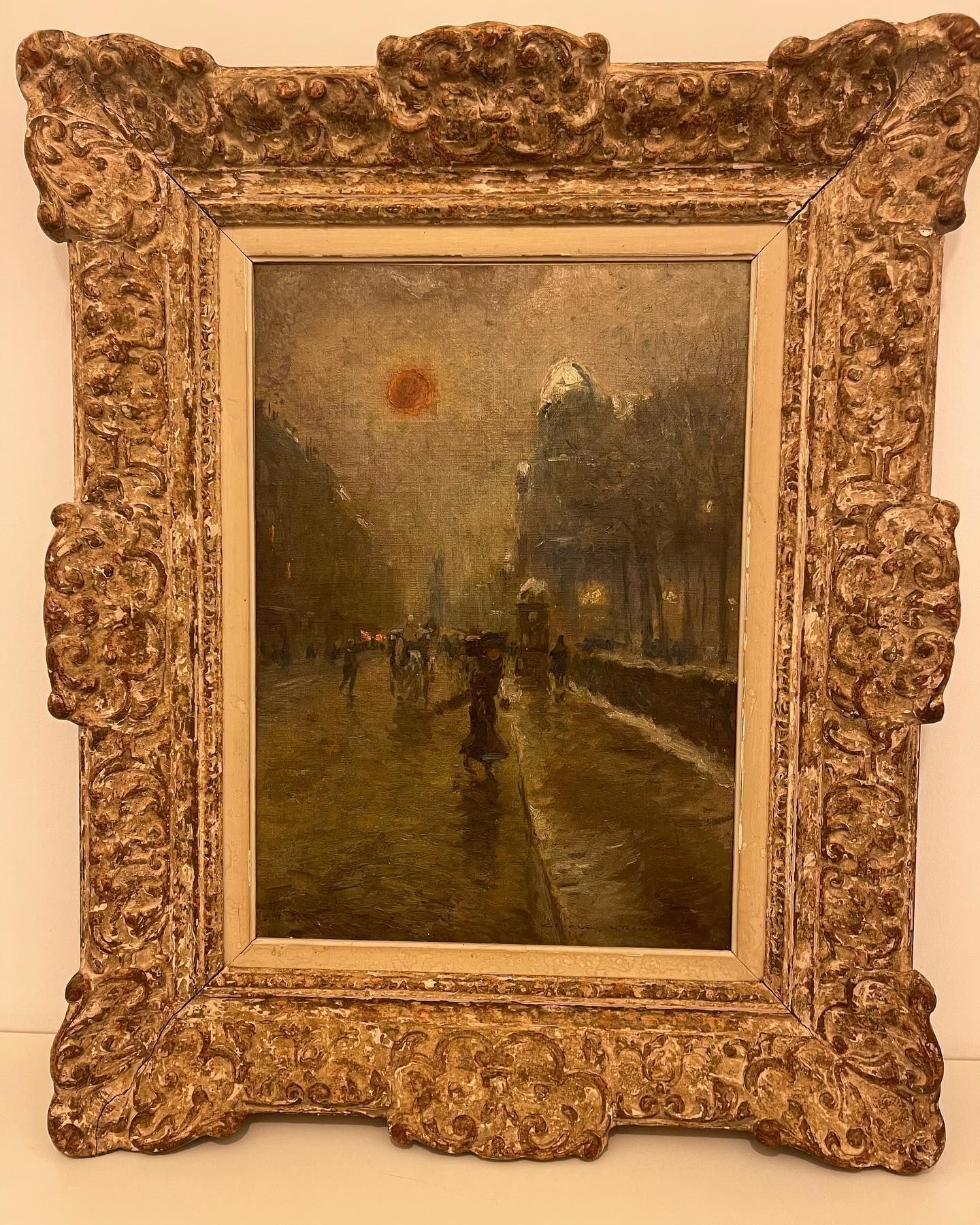 Peinture à l'huile représentant une rue parisienne sous la pluie, avec un soleil rouge, encadrée d'or orné.
