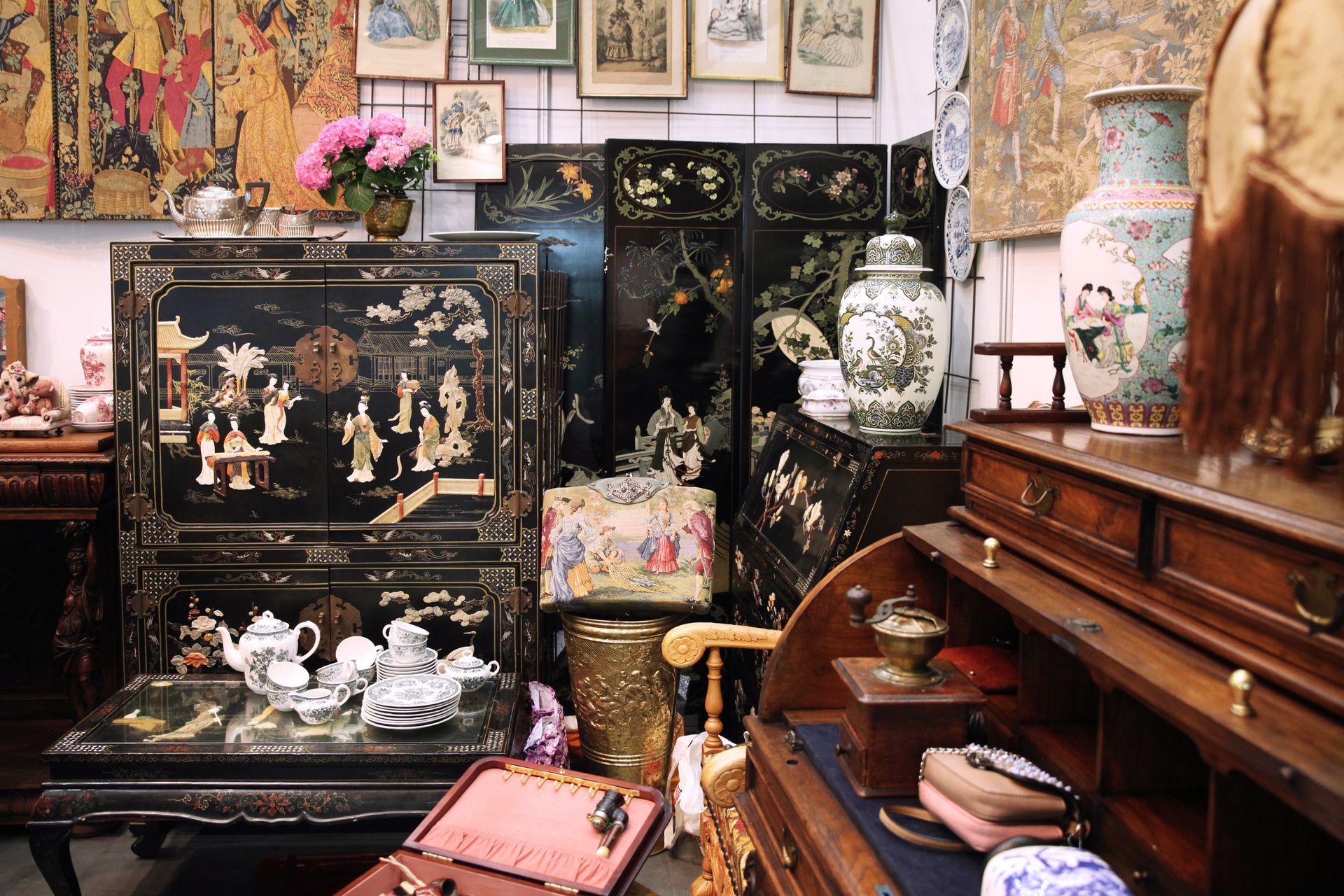 Intérieur d'un magasin d'antiquités avec meubles ornés, paravents, vases et œuvres d'art encadrées.
