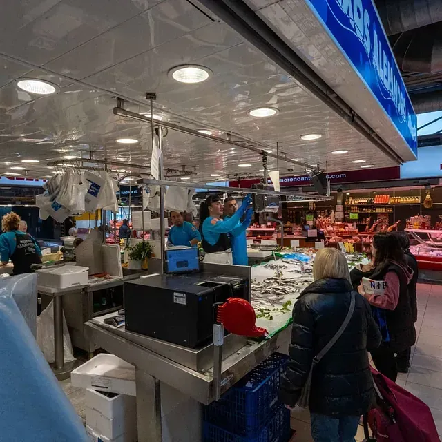 Un grupo de personas están de pie alrededor de un mercado de pescado.